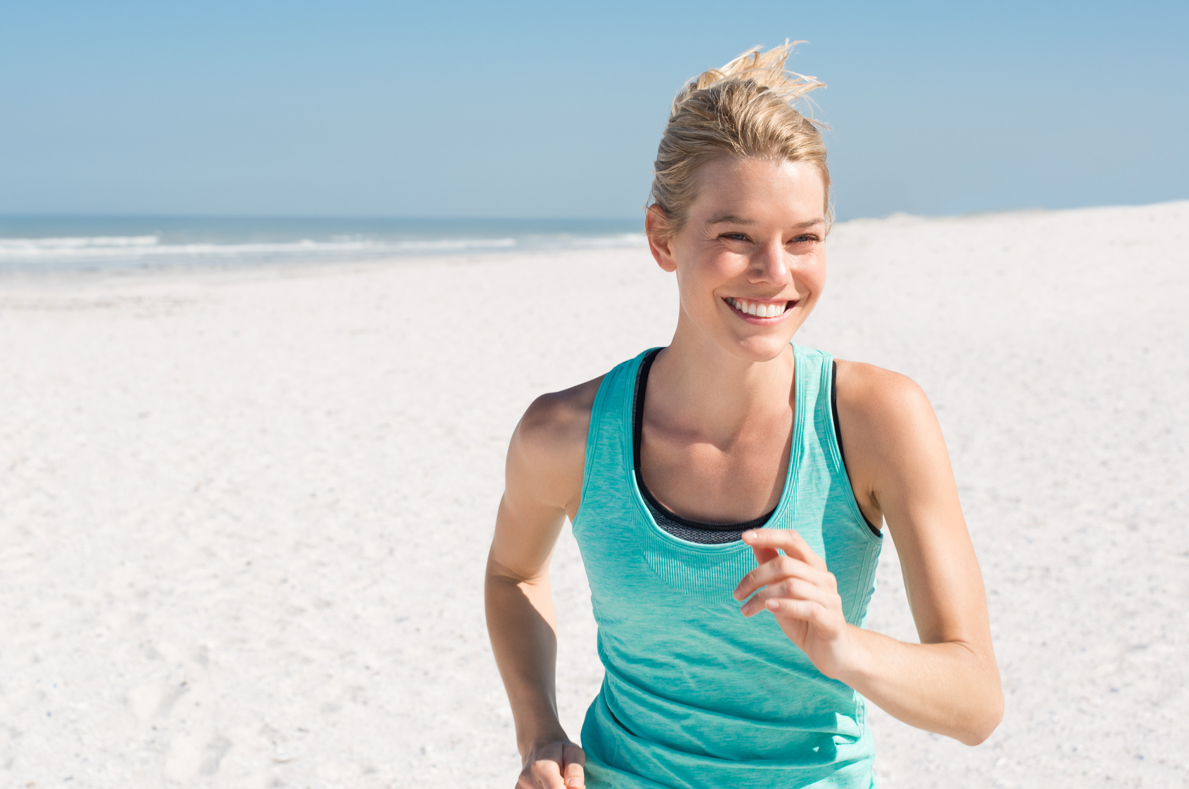 Female runner jogging during the morning on beach. Beautiful young woman running at summer morning. Beautiful fitness girl exercising outdoors.